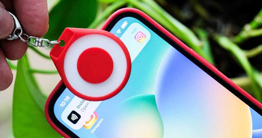 A red TapTag held to an iPhone, with an Instagram link notification on screen